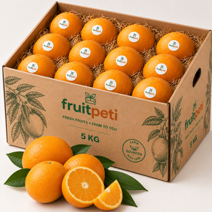 A 5 kg cardboard box filled with oranges on a white studio background, with several oranges and green leaves placed in front of the box. The box is branded fruitpeti.