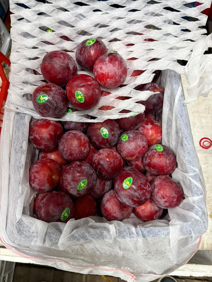Fresh red plums close up in box